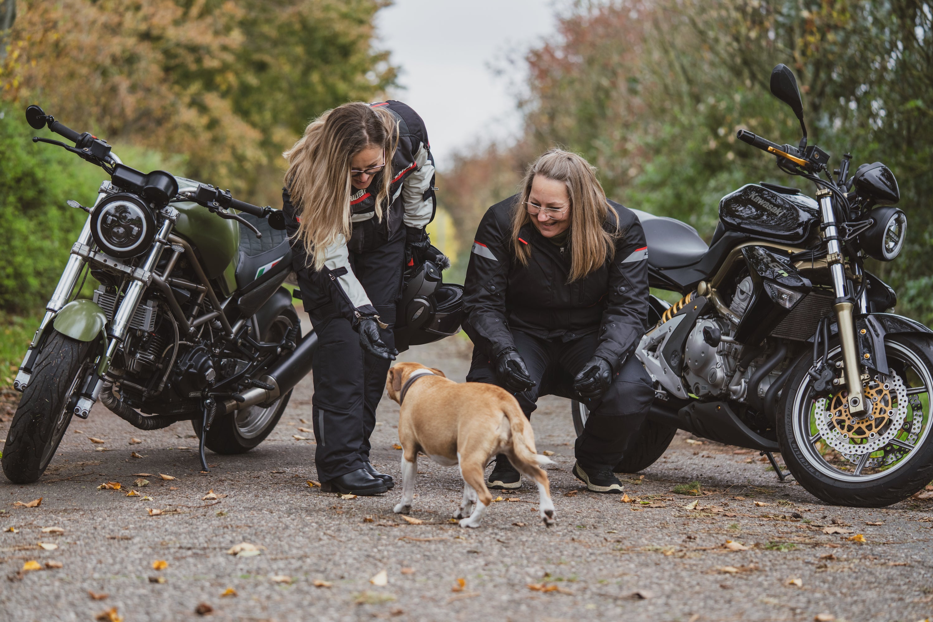 Women motorcyclists greeting a dog 