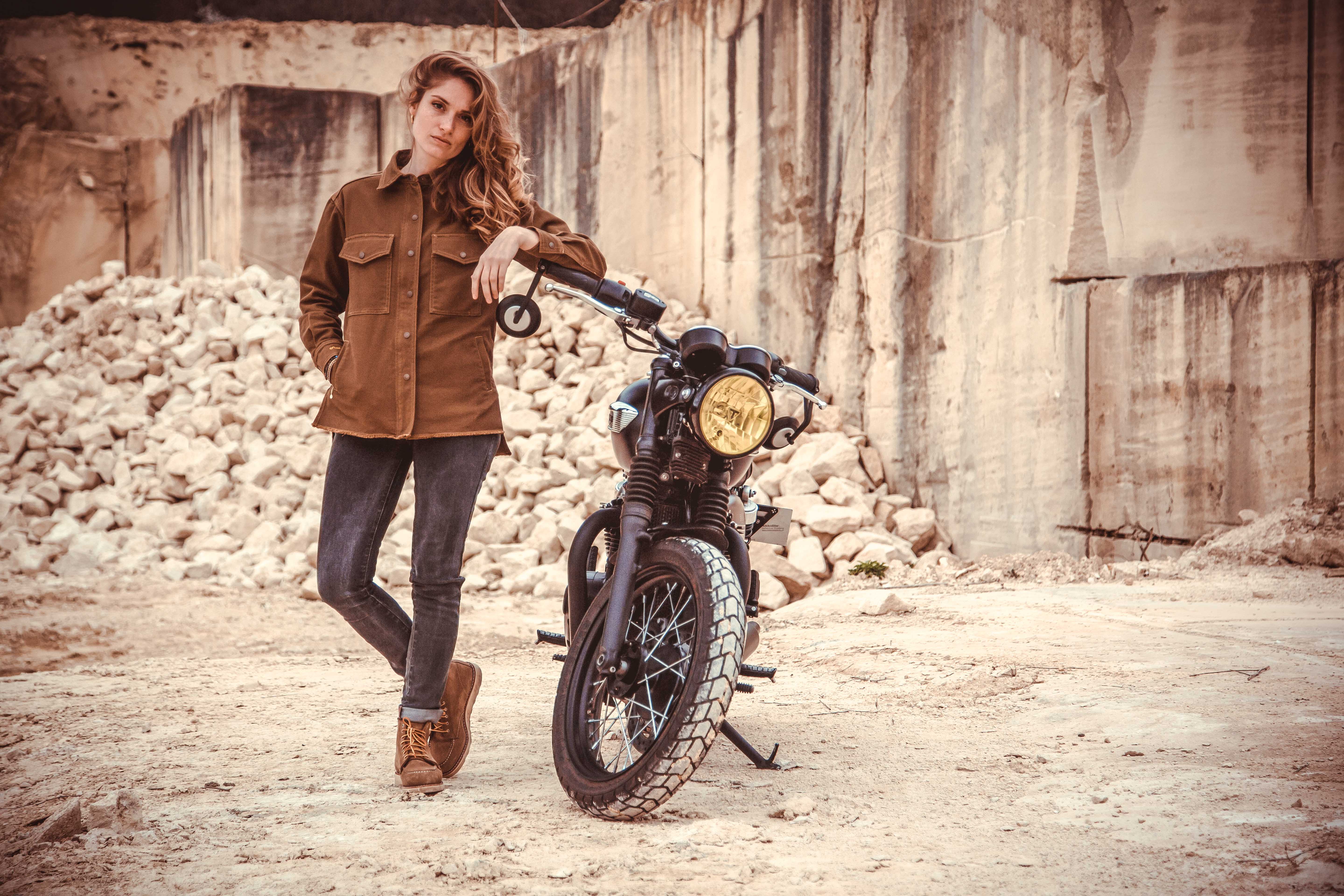 a woman leaning on a motorcycle wearing brown khaki denim mc shirt