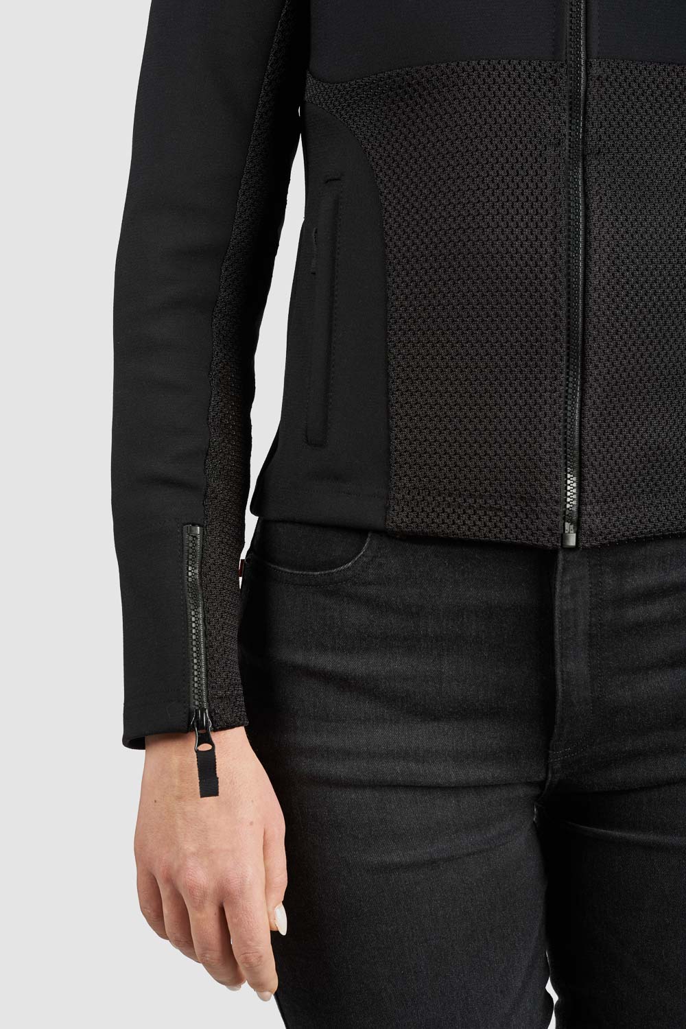 Person wearing a black jacket with textured panels on a white background