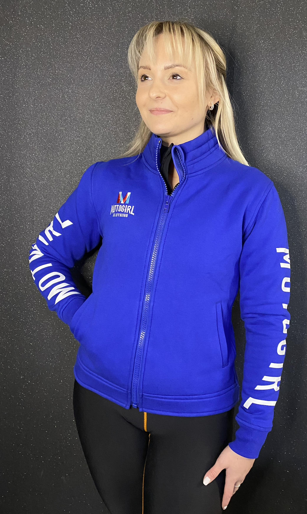 a blond woman wearing Motogirl clothing blue sweatshirt with a front zip