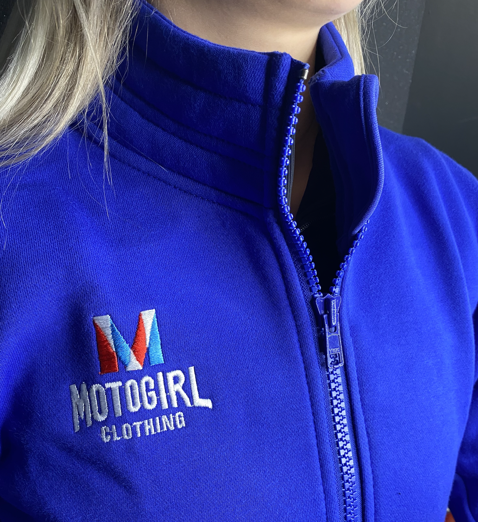 close up of woman's neck wearing Motogirl clothing blue sweatshirt with a front zip