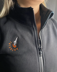 a close up of a woman's neck wearing black sweatshirt with a zip and MotoGirl embroidery 