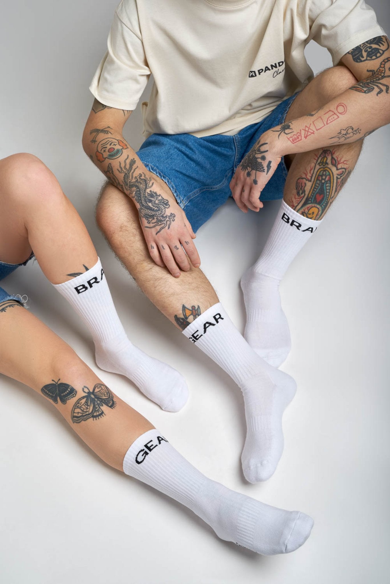 man and women tattood legs wearing white socks  with "break" and "gear"