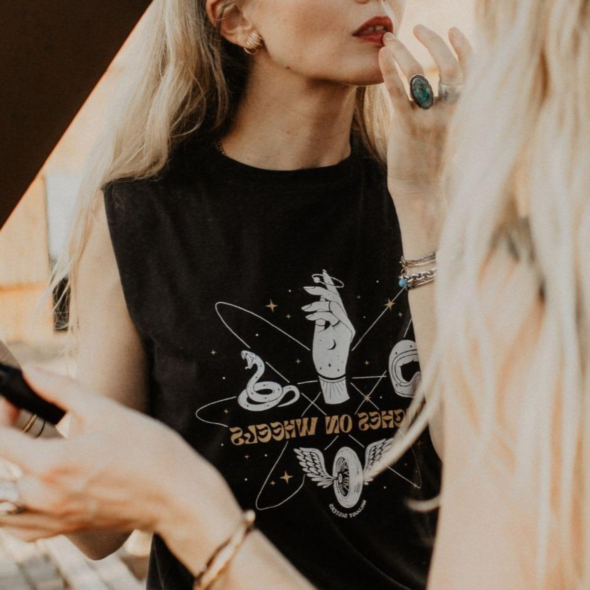 a young blong woman putting her lipstick on and wearing tank top with motorcycle motives