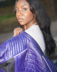 a black woman holding her purple motorcycle leather jacket on the shoulder