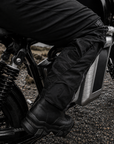 Person wearing black motorcycle boots and pants on a motorcycle.
