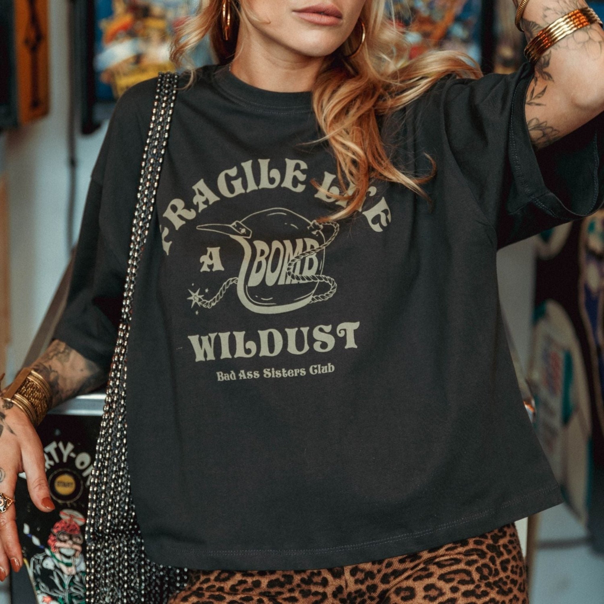 a young woman wearing off-black wide cut short sleeve women's motorcycle t-shirt with helmet motive and Fragile like a bomb  logo 