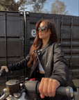 a young lady on a motorcycle wearing Black retro style woman's motorcycle jacket with silver zip details