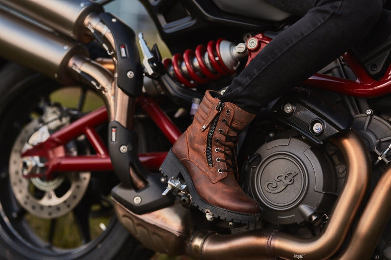 woman&#39;s foot on a motorcycle rest wearing brown leather mc boots 