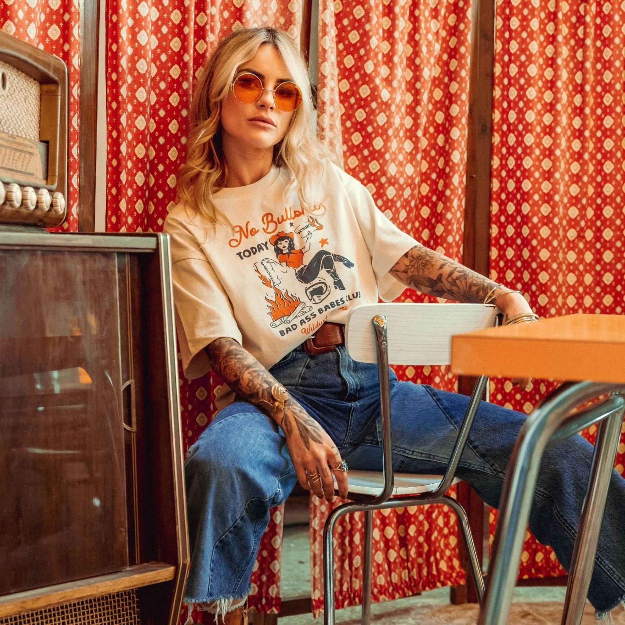 a woman wearing off white/creame colour t-shirt with retro motive that says No bullshit