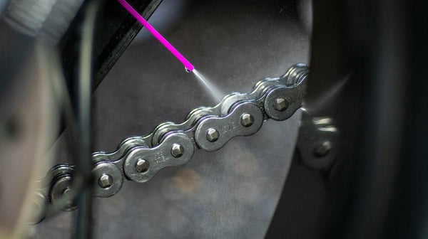 motorcycle chain being sprayed with the muc-off Dry chain lube for motorcycles and scooters