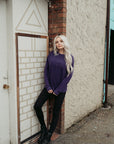 A young woman standing by a wall and wearing purple colour lady sweatshirt with Moto Girl 3D logo