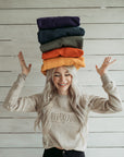 a young woman wearing Sand colour lady sweatshirt with Moto Girl 3D logo and holding 5 colourful sweatshirts on her head