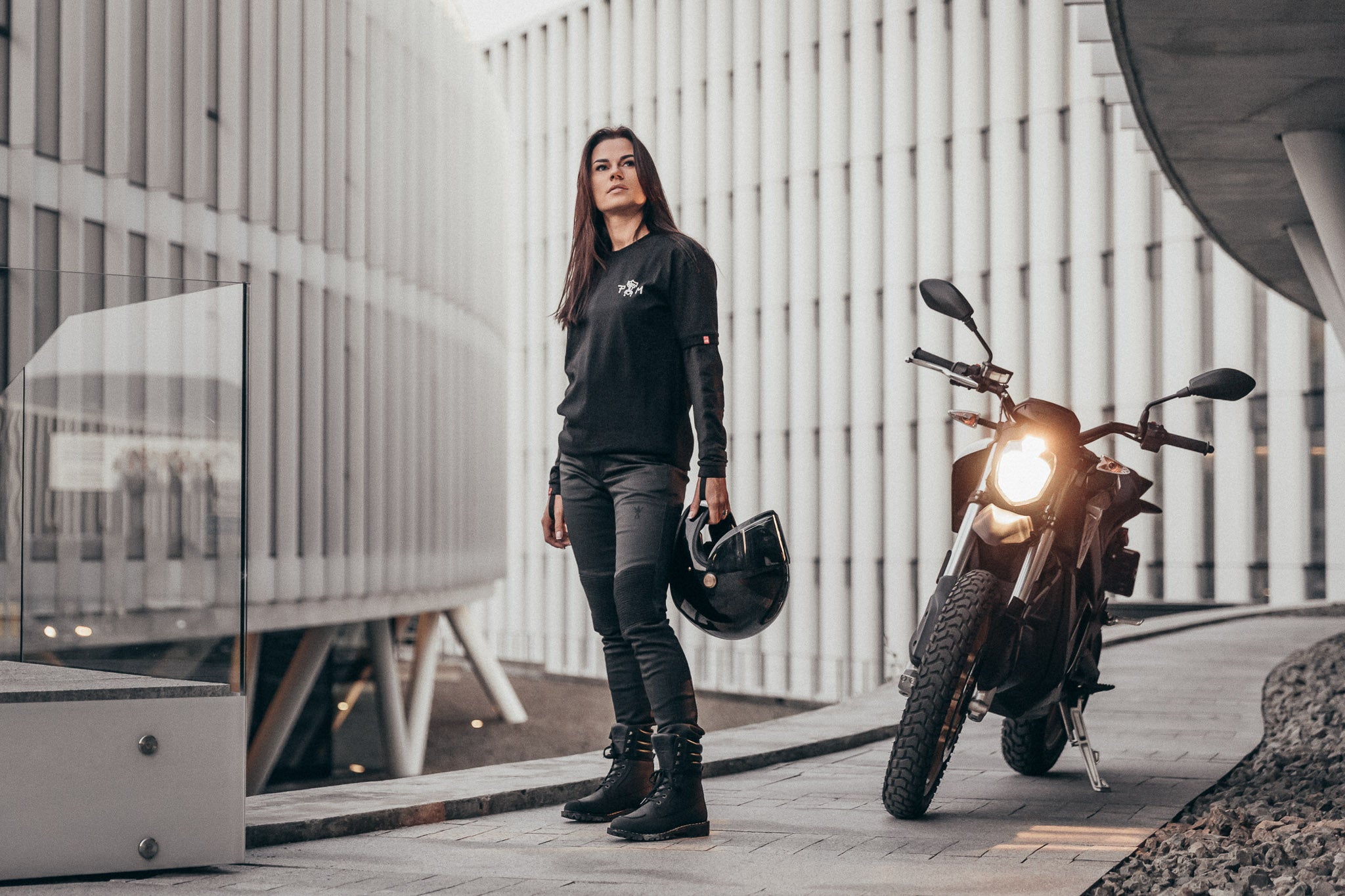 A woman standing by a motorcycle wearing Pando Moto motorcycle clothes