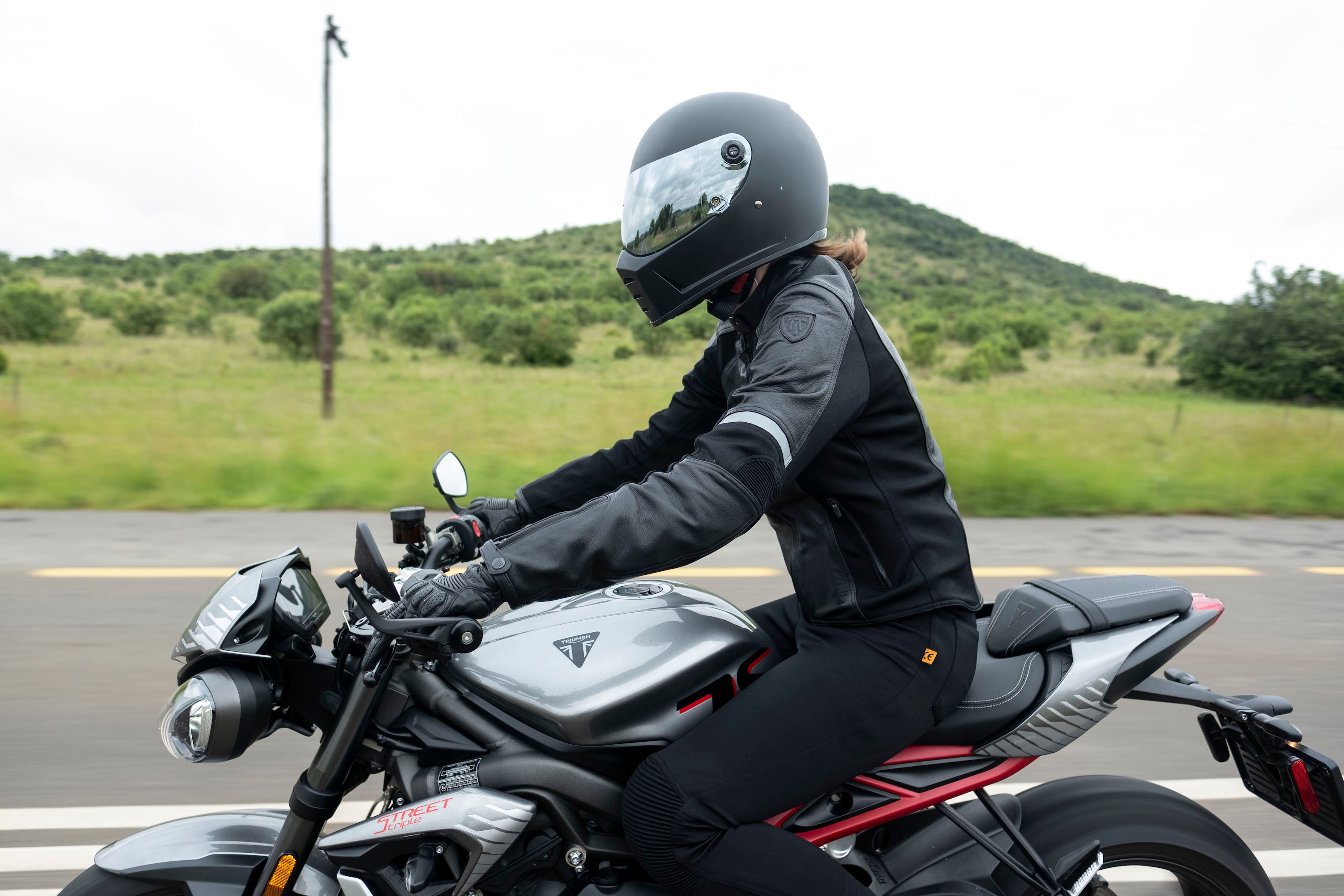 A woman driving a motorcycle wearing Black leather women&#39;s motorcycle jacket with reflectors from Moto Girl 