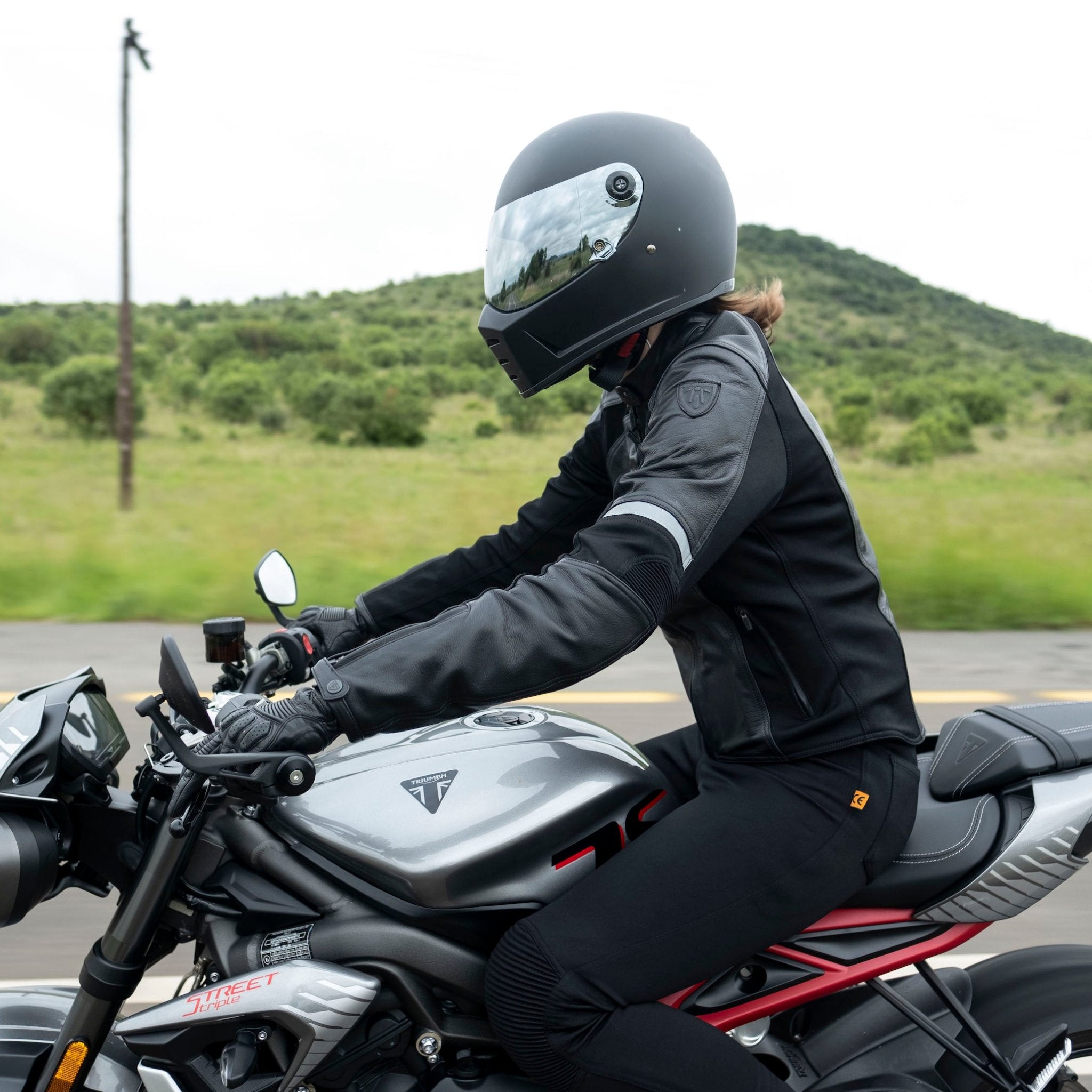 A woman driving a motorcycle wearing Black leather women&#39;s motorcycle jacket with reflectors from Moto Girl 