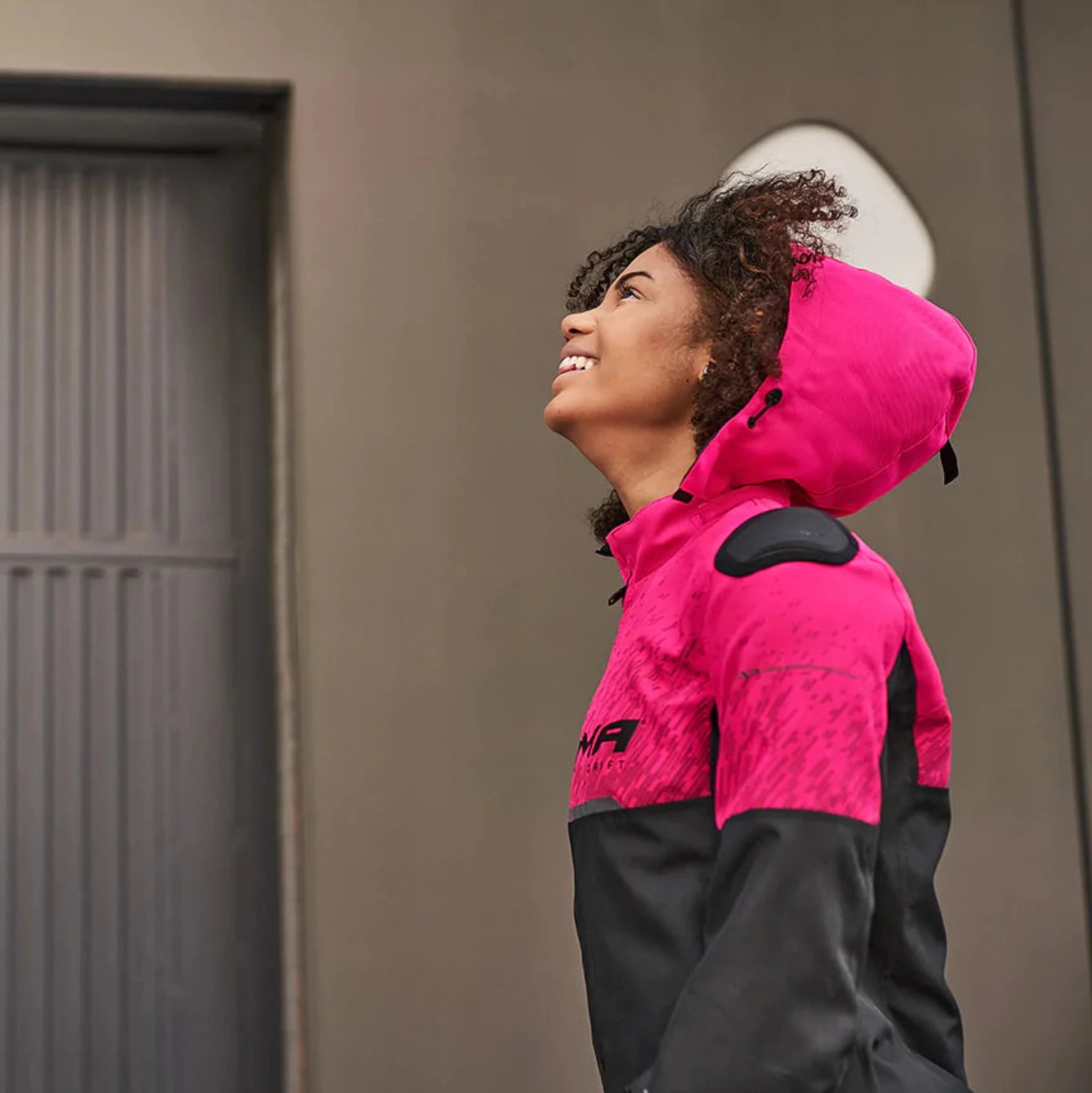 A young afroamerican woman wearing pink motorcycle jacket with the hood 