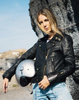 A young woman holding a helmet and wearing Classic retro black women's motorcycle jacket from Eudoxie