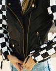 A close up of a woman zipping her chessboard style motorcycle jacket 