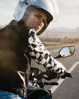 a young woman driving a motorcycle wearing chessboard design mc jacket