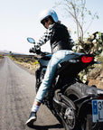 A woman on a motorcycle wearing a Chessboard design leather motorcycle jacket from eudoxie