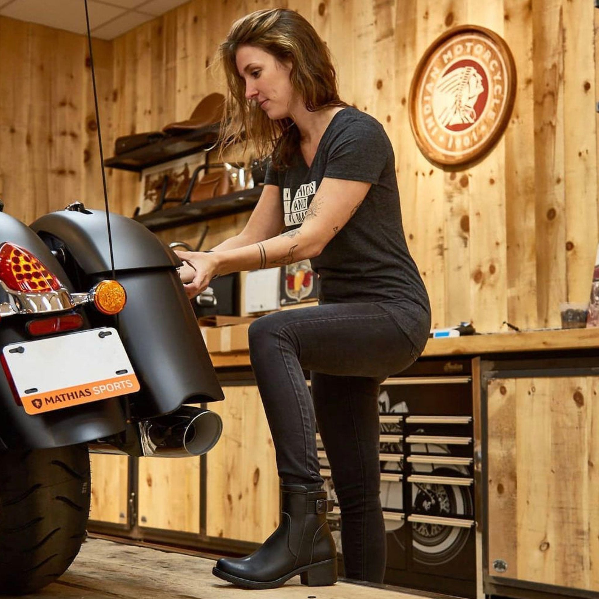 Woman mechanic in the garage wearing women&#39;s black leather motorcycle shoes 