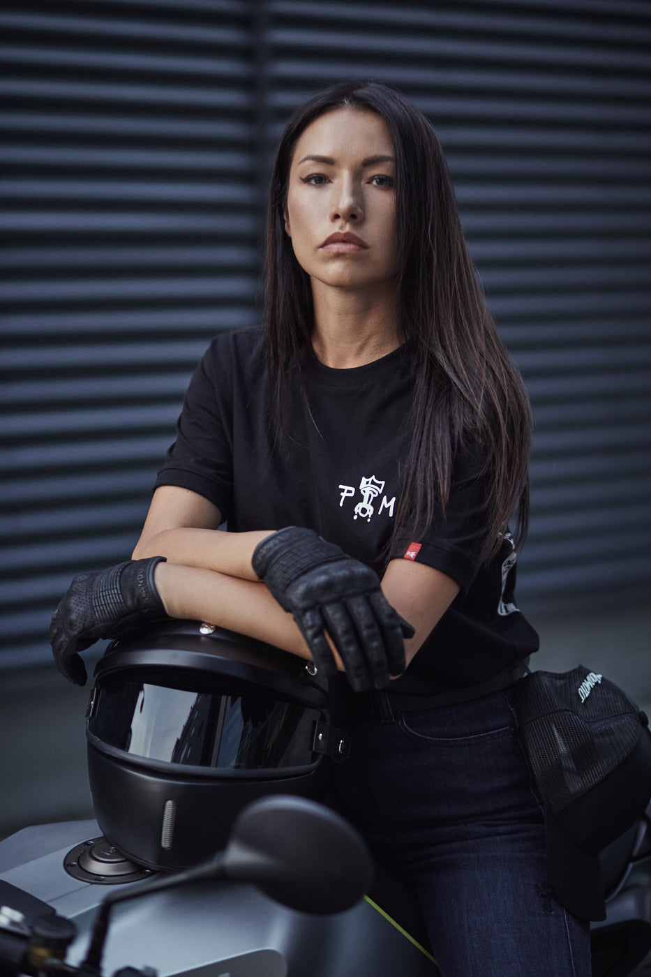 A young woman on a motorcycle leaning on a helmet