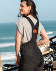 A woman by the beach with her motorcycle wearing Black women's motorcycle overall from Moto Girl
