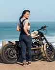 A woman by the beach with her motorcycle wearing blue women's motorcycle overall from Moto Girl