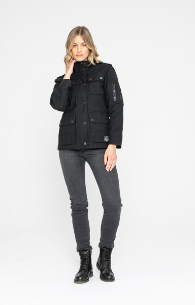 A woman wearing grey jeans and BLACK army style women's motorcycle jacket from John Doe