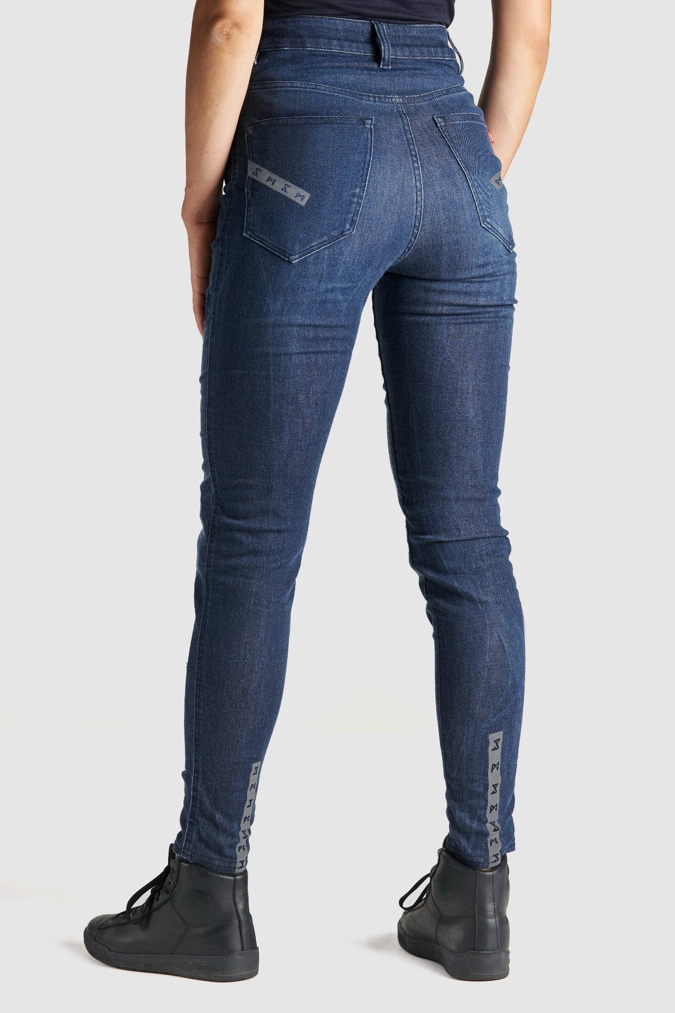 Woman's legs from the back wearing blue motorcycle jeans 