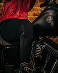 Close up of a woman's, sitting on the motorcycle and wearing black motorcycle leggings,  knee 
