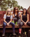 Three women wearing motorcycle overalls siting on the bed of a truck