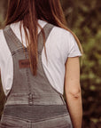 A back of a woman wearing white tshirt and grey motorcycle overall 