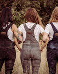 Three women wearing motorcycle overalls standing side by side in the field