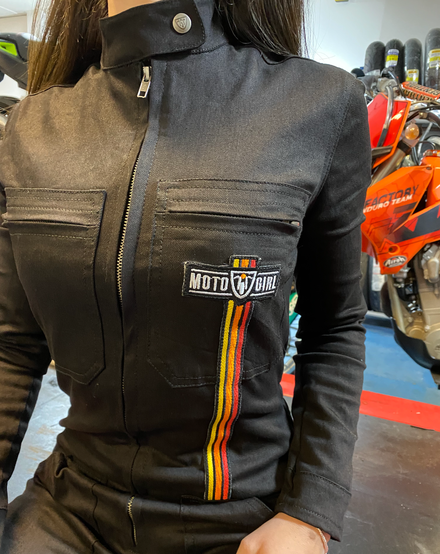 A close up of a woman&#39;s chest wearing black women&#39;s garage jumsuit with MotoGirl logo