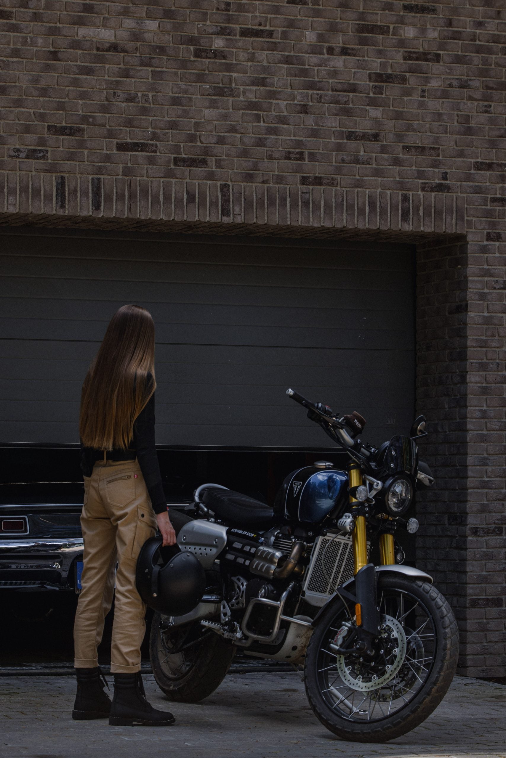 a woman standing by her motorcycle wearing beige mc pants