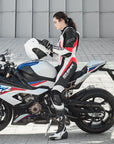 A young woman on a bmw racing motorcycle wearing Women's racing suit MIURA RS in black, white and fluo from Shima  