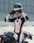 A woman putting her helmet on and wearing Women's racing suit MIURA RS in black, white and fluo from Shima 