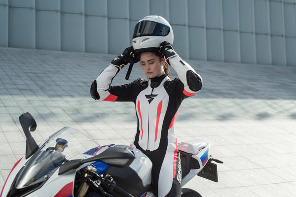 A woman putting her helmet on and wearing Women's racing suit MIURA RS in black, white and fluo from Shima 