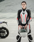 A young woman standing near a motorcycle wearing Women's racing suit MIURA RS in black, white and fluo from Shima 