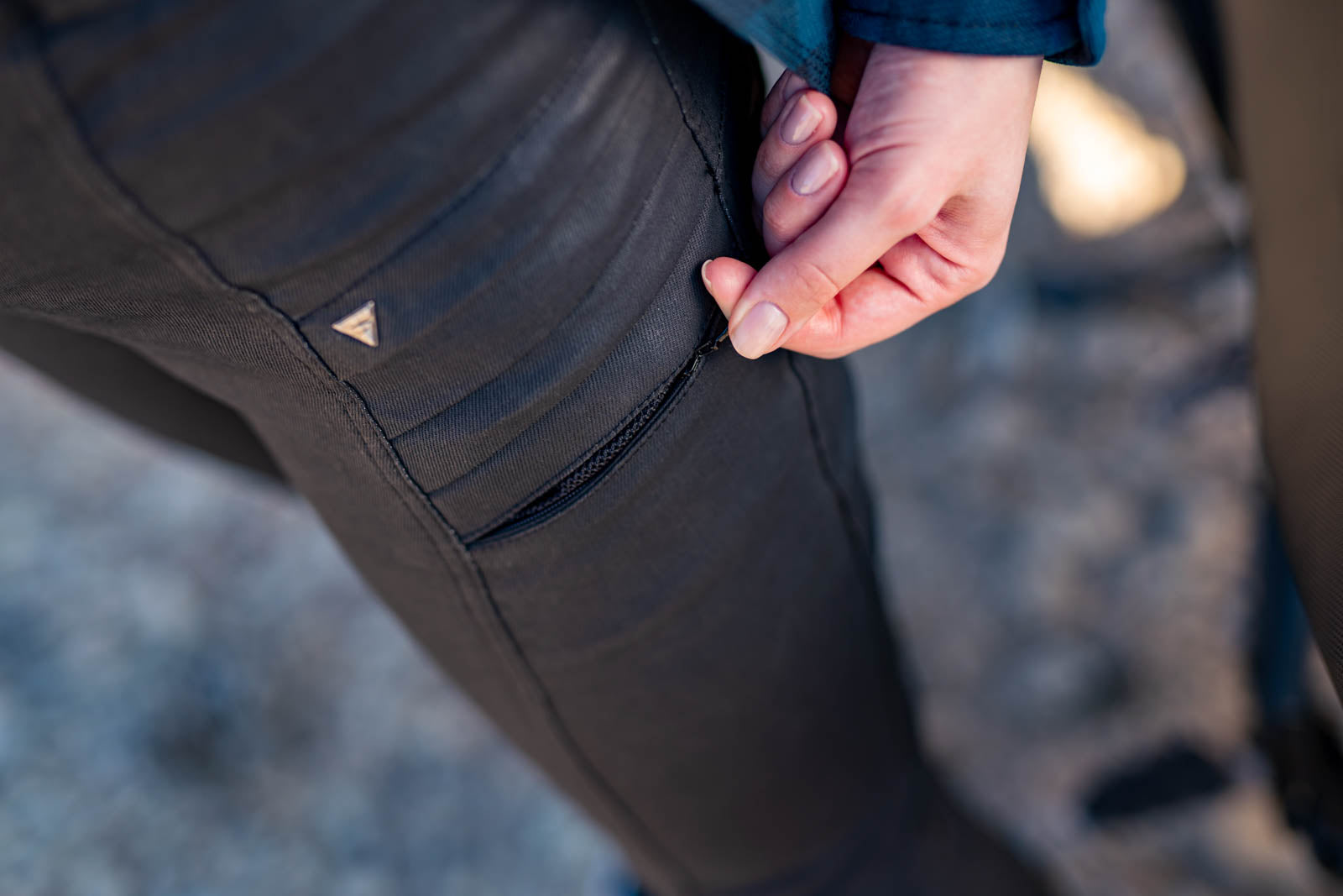 woman&#39;s hand zipping a pocket on lady motorcycle trousers