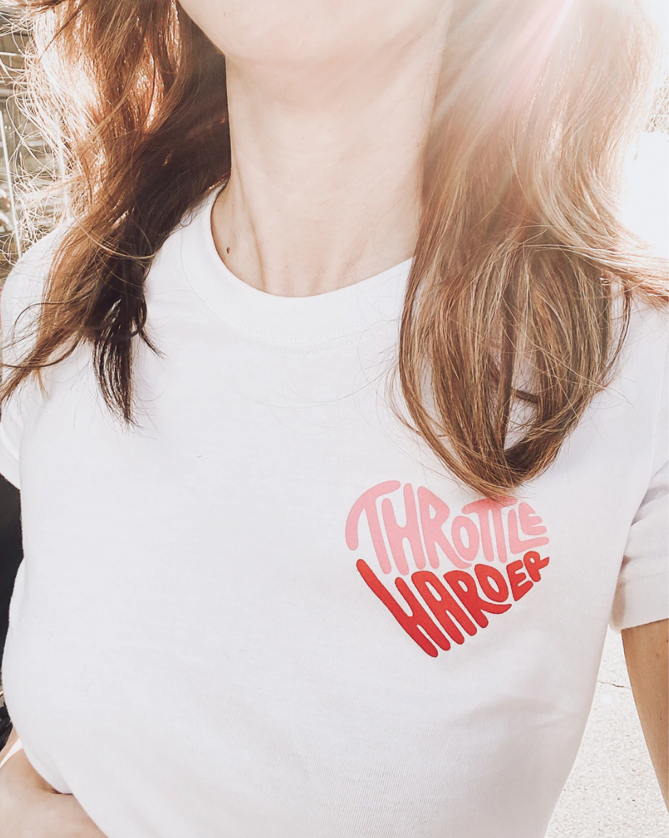A woman&#39;s chest wearing white Throttle harder t-shirt from Black Arrow Label