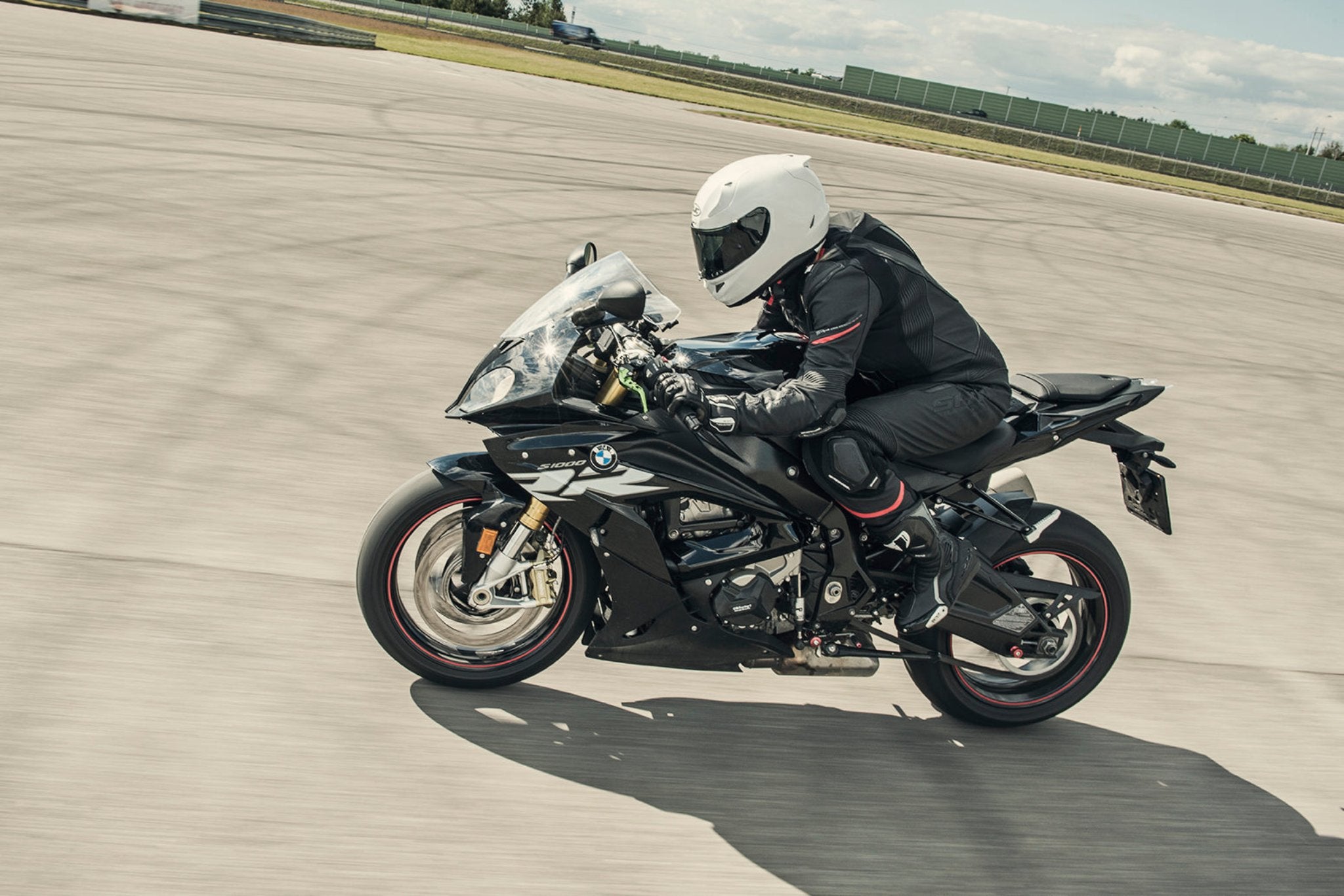 A woman racing on a motorcycle wearinh Black and red women's motorcycle racing suit from Shima