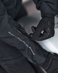 woman's hand wearing black summer motorcycle gloves zipping the sleeve of a motorcycle jacket 