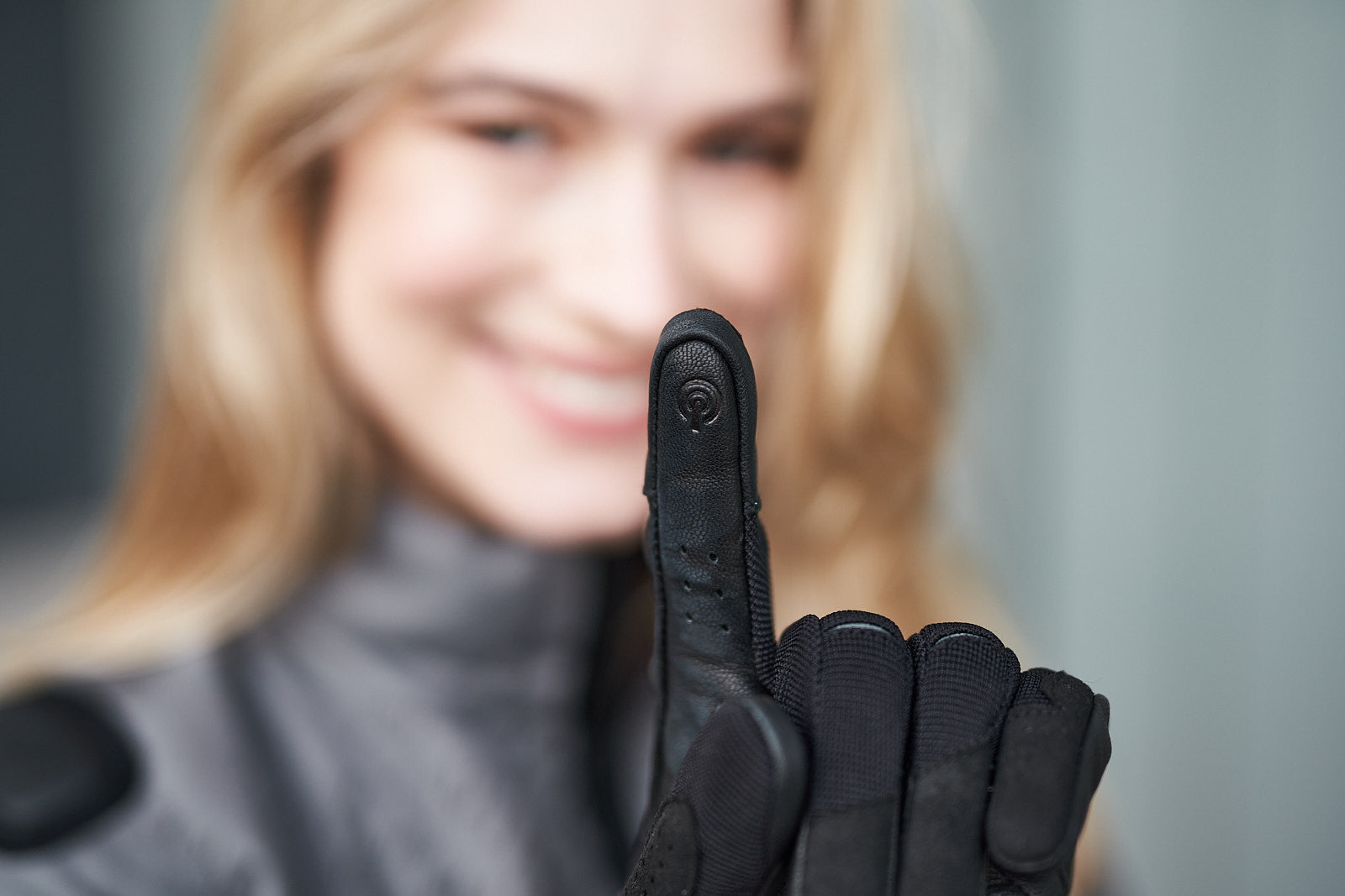 a woman&#39;s finger wearing black motorcycle glove with touch pad panel