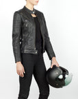 A woman holding a helmet and wearing Women's black leather motorcycle jacket modern classic style from Black arrow label