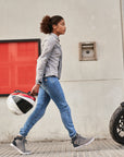 Young woman wearing Light blue motorcycle jeans for women walking towards her motorcycle
