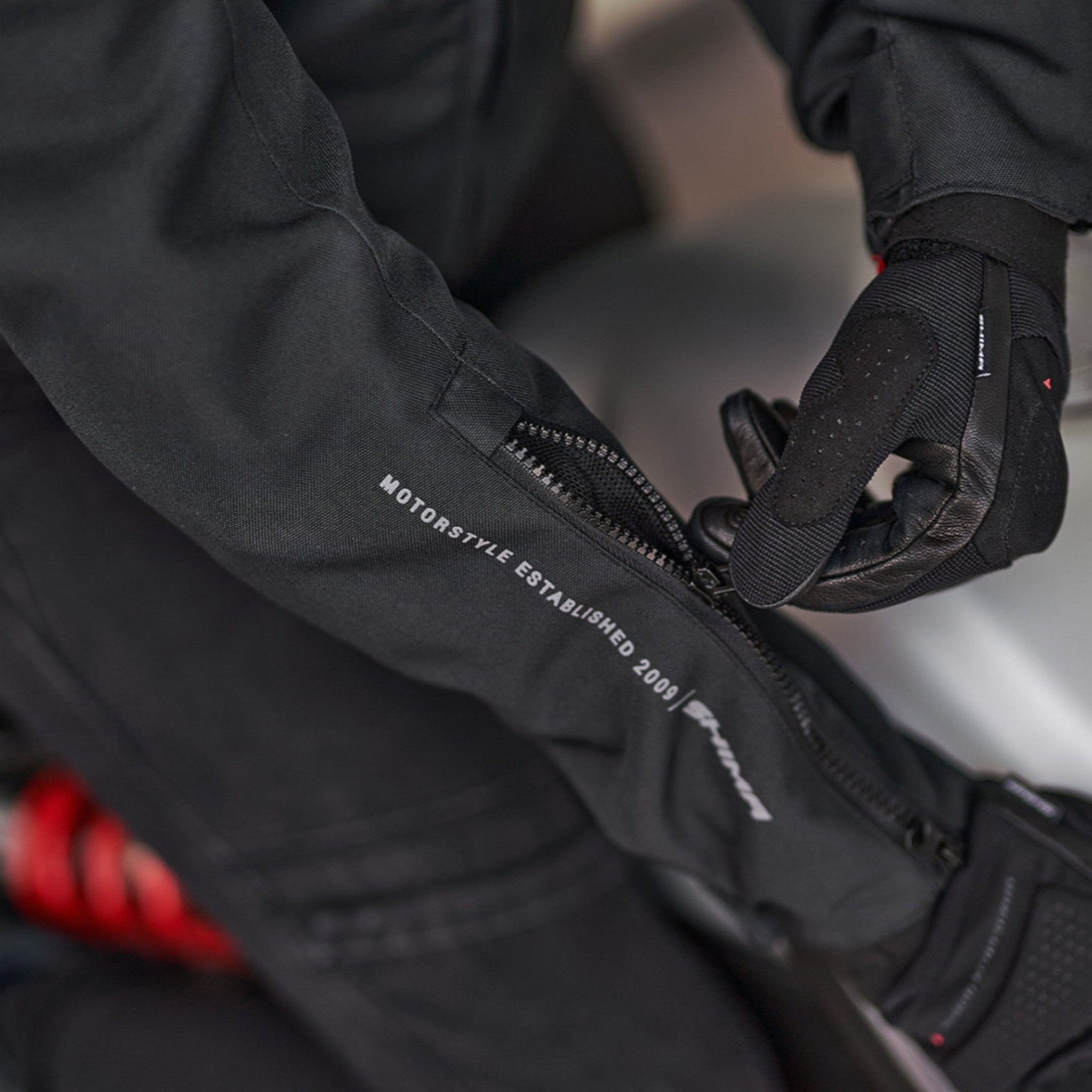 Woman's hands zipping the sleeve of the motorcycle jacket