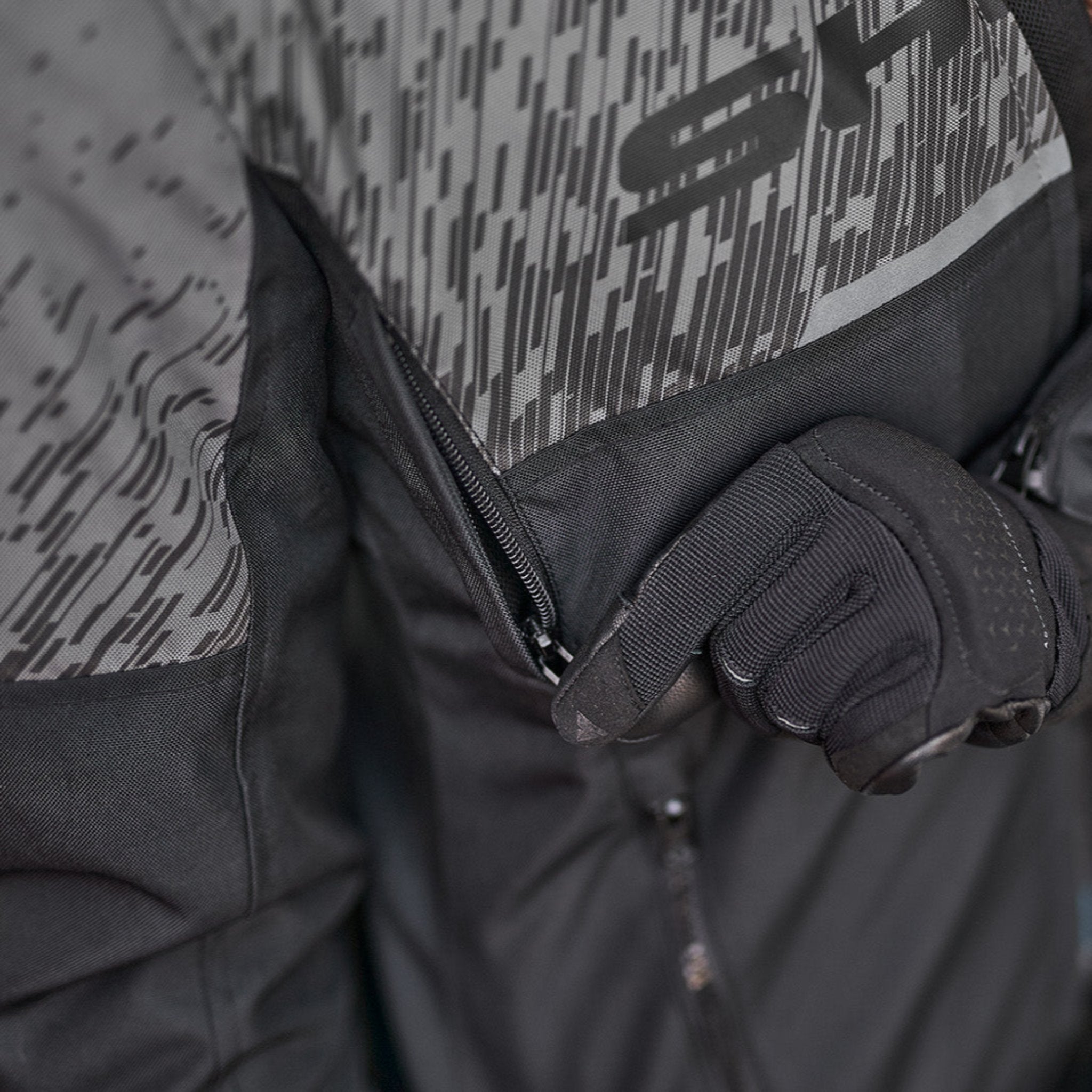 a hand unzipping the ventilation panel on the grey women&#39;s motorcycle jacket from SHIMA